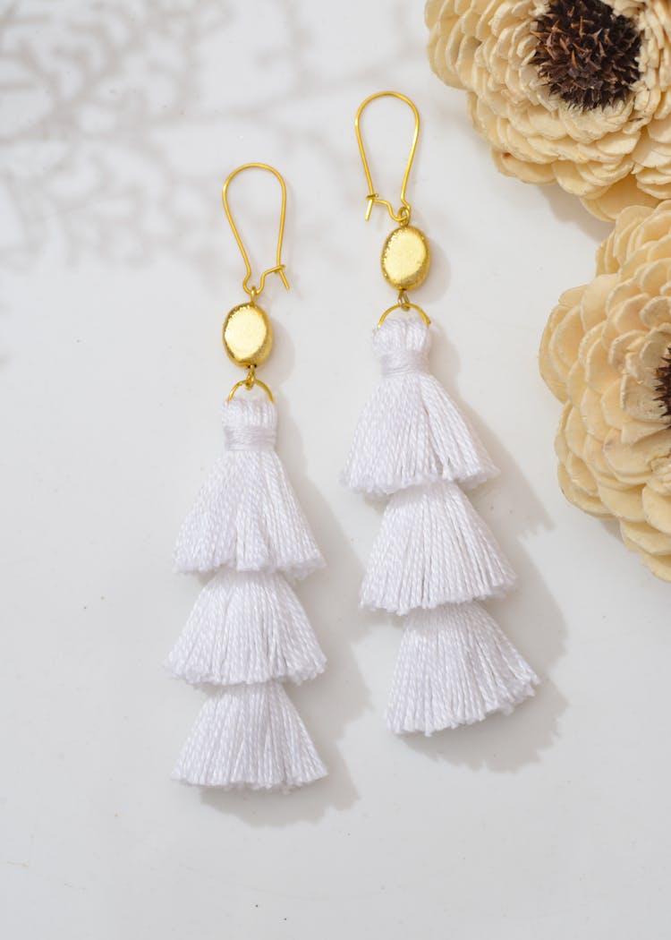 Close-Up Shot Of White Dangle Drop Tassel Earring On White Surface