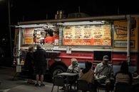 People Sitting on Chair Near Food Stall during Night Time