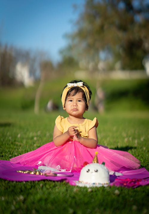 Free Girl in Pink Dress Sitting on Grass Field Stock Photo