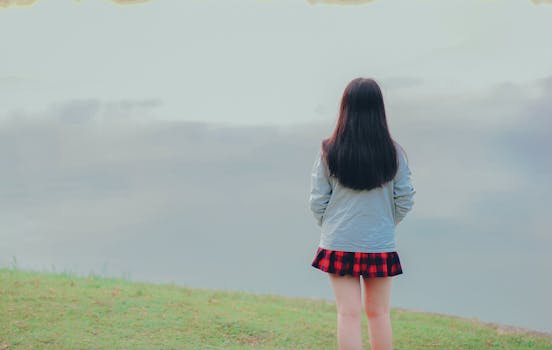 日落时分，一名女子站在雾气缭绕的湖边，拥抱孤独，沉浸于自然的宁静之中