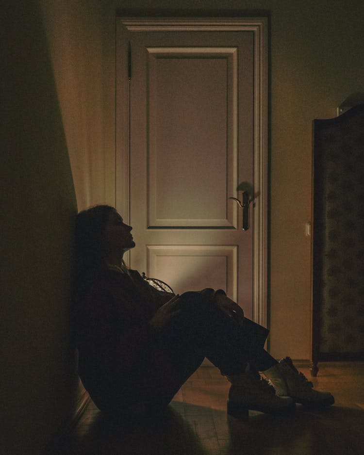 A Person Sitting On Floor Beside A Door