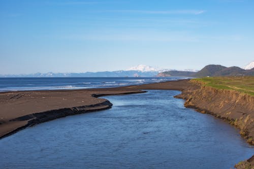 Ocean near Mountains under the Blue Sky