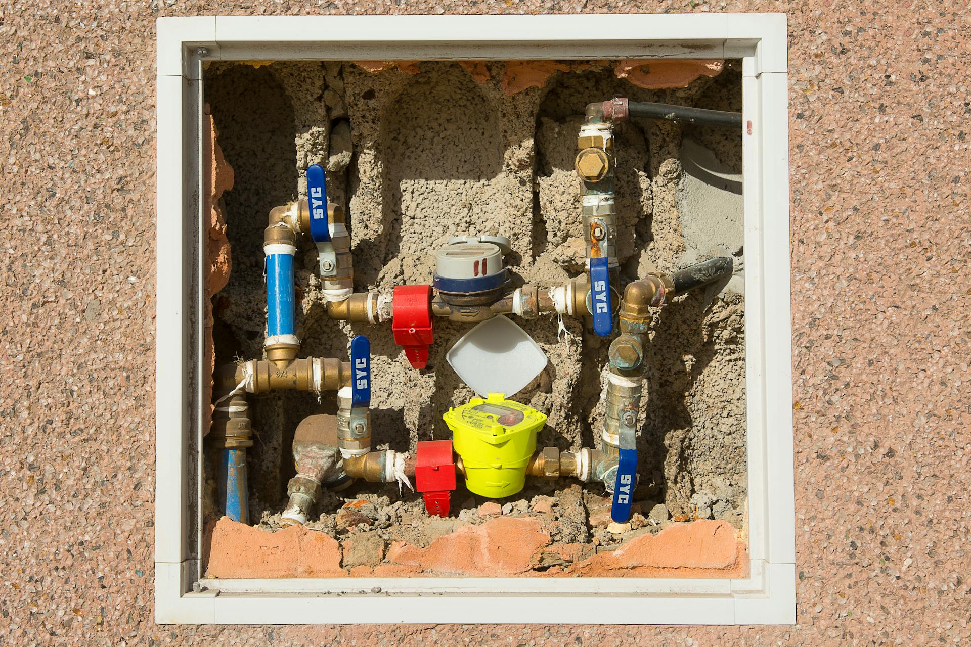 Detailed view of a complex water meter setup embedded in a concrete wall.