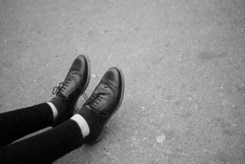 Grayscale Photo of a Person Wearing a Leather Shoes