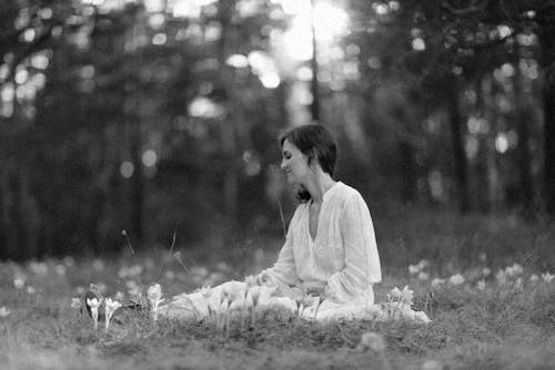 Grayscale Photo of a Woman Sitting on the Grass