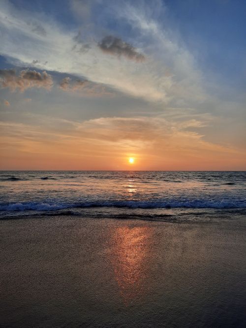Free Tranquil sunset at Gokarna Beach, India with ocean waves and warm skies. Stock Photo