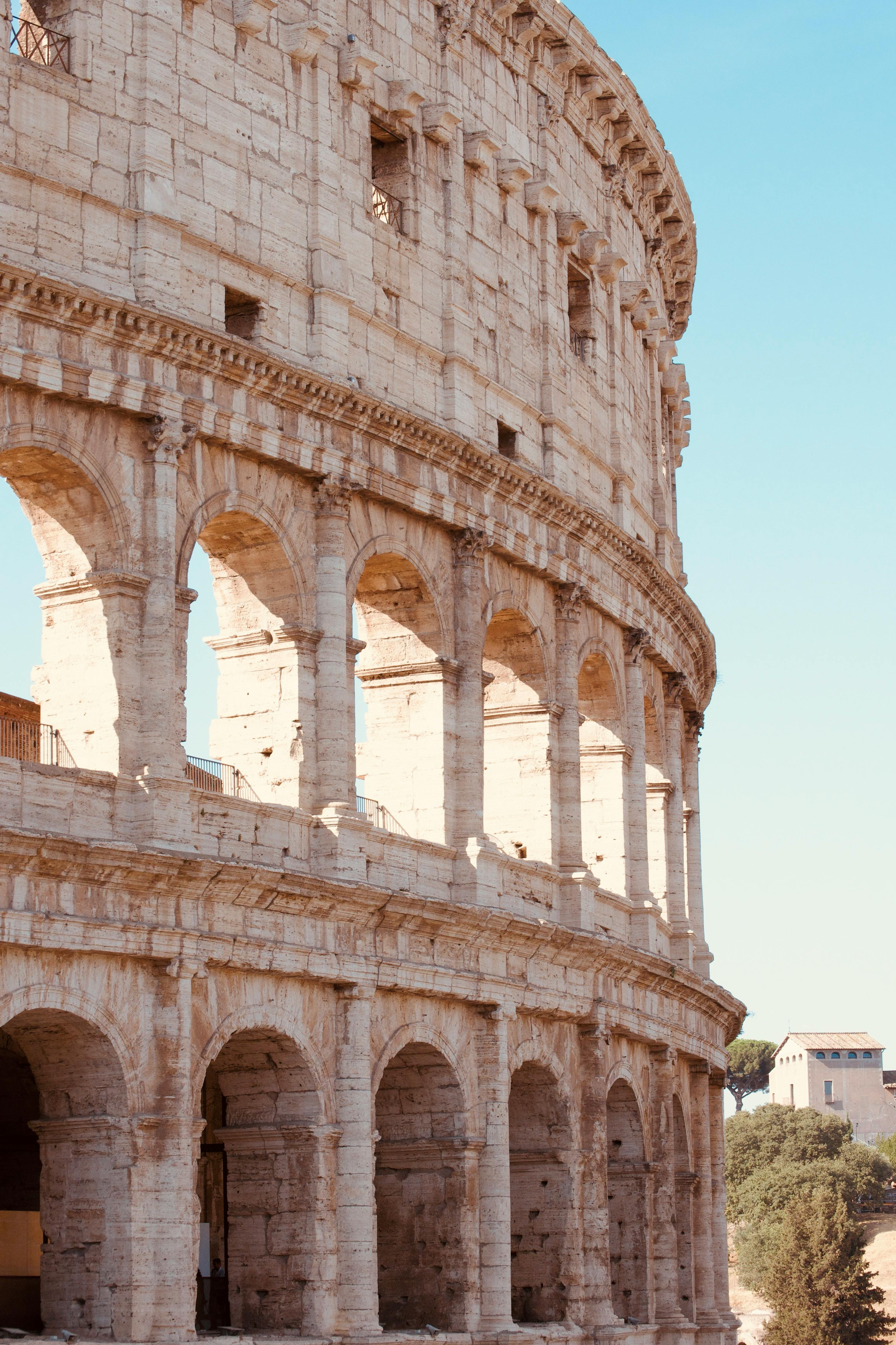 Free A stunning view of the ancient Colosseum's arches under a clear sky in Rome. Stock Photo