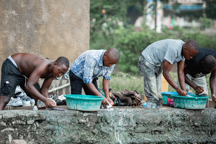 Shallow Focus Of Four Men Washing Shoes