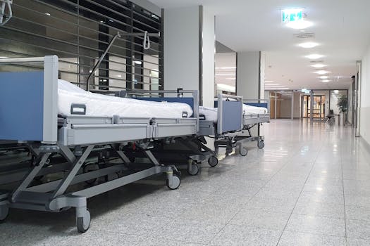 Quiet hospital hallway with neatly arranged empty medical beds under bright ceiling lights.