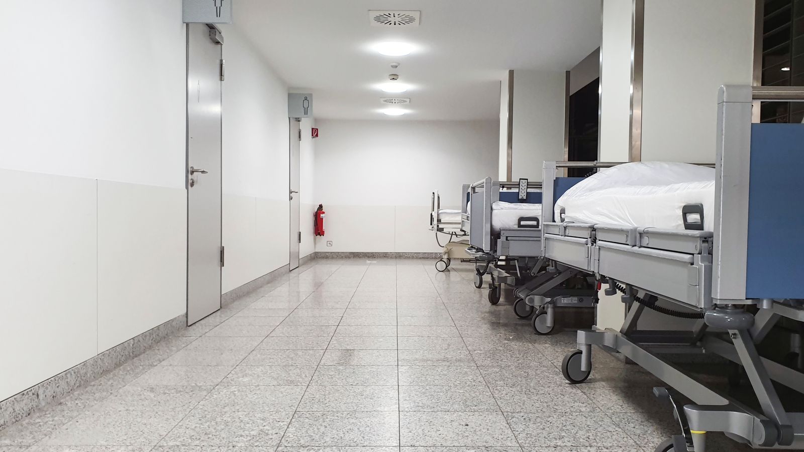 Modern hospital corridor with empty medical beds and sterile environment.