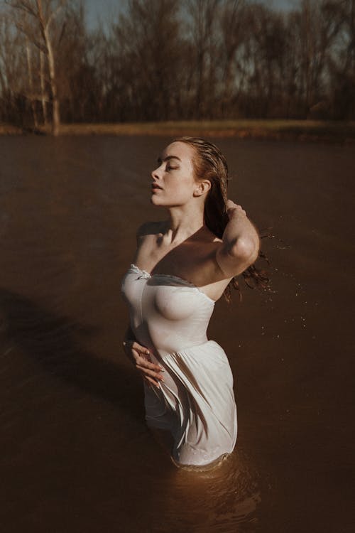 Woman Standing in Water in Wet White Dress