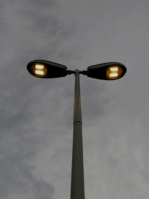 Free Low-angle view of a street light illuminating against a dramatic cloudy sky. Stock Photo