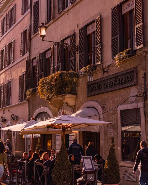 Free People enjoy a sunny day at a historic outdoor cafe with classic architecture. Stock Photo