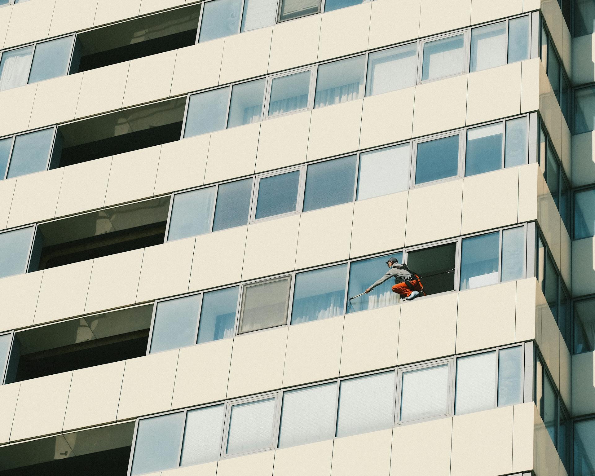 A window cleaner working on a tall urban building facade in Dnipro, Ukraine.