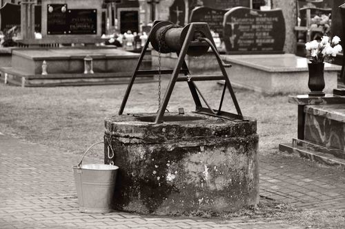 Free Grayscale image of a vintage water well in a cemetery in Samogoszcz, Poland. Stock Photo