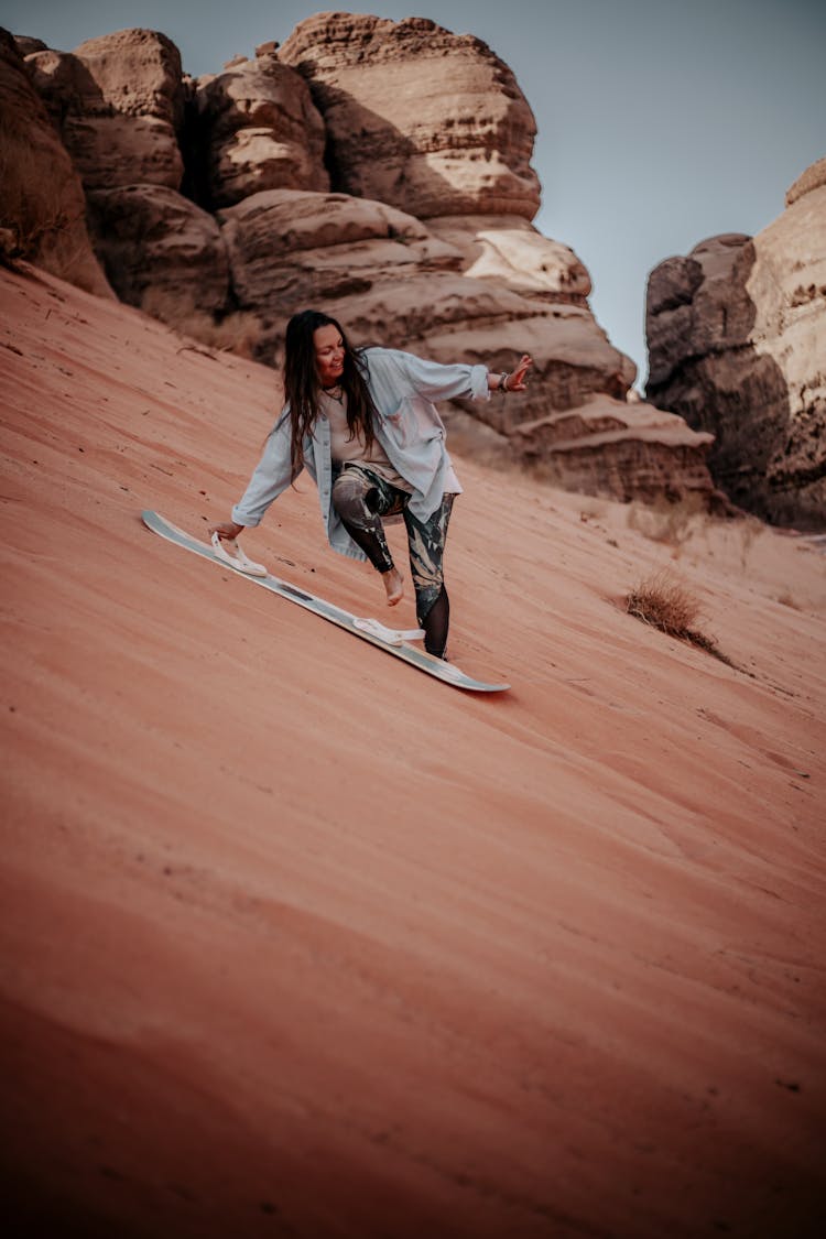 A Woman Sandboarding On Desert