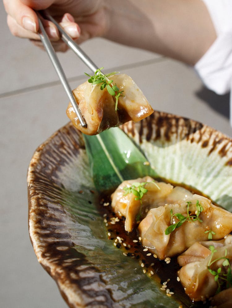 Woman Eating Gyoza Dumplings With Chopsticks