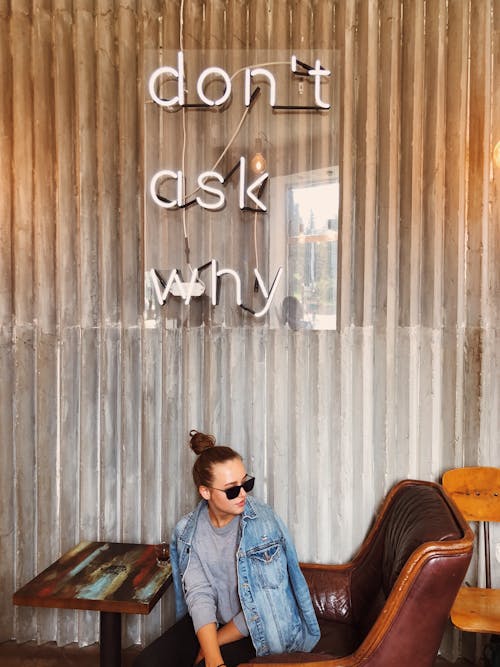 A Woman in Denim Jacket and Black Sunglasses Sitting on the Chair