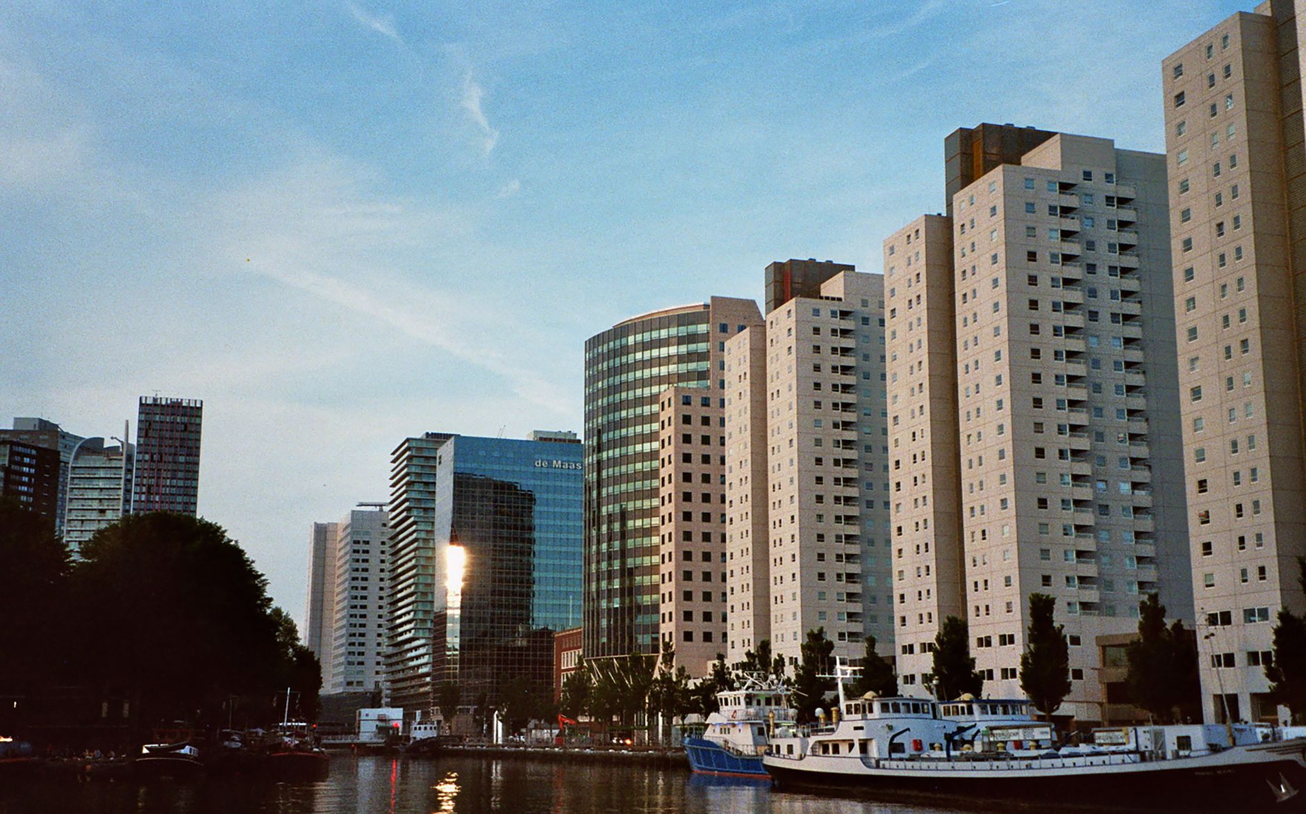 Stunning view of Rotterdam's urban skyline under a clear blue sky. Modern architecture and waterways visible.