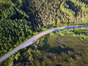 夏季，无人机在苏格兰高地郁郁葱葱的森林中，拍摄了一条蜿蜒道路的镜头