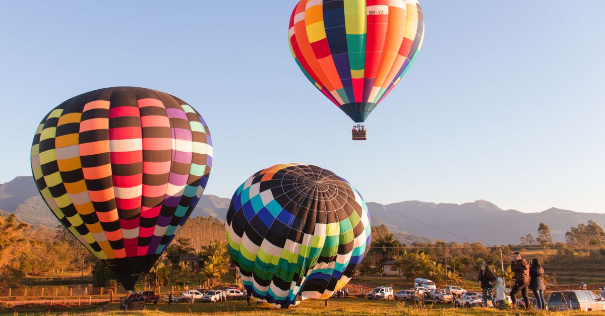 Vibrant hot air balloons taking off in a scenic Brazilian setting under a clear sky.
