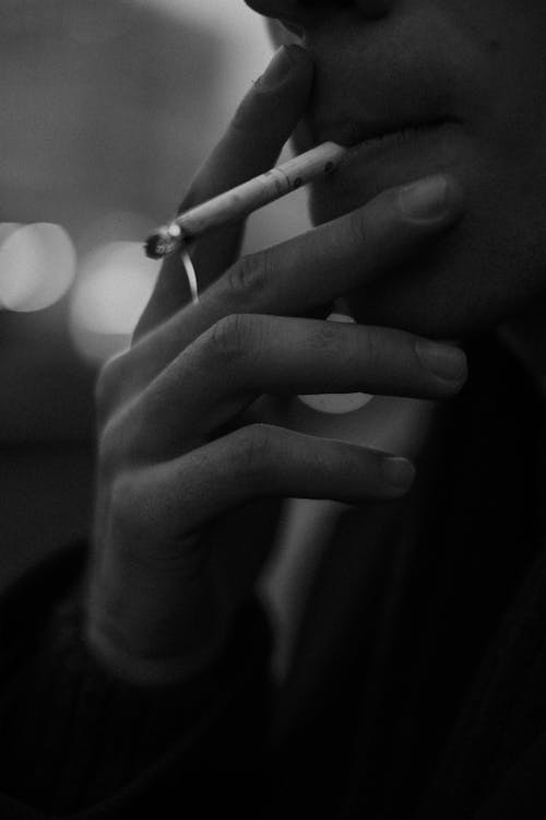A Grayscale Photo of a Person Smoking Cigarette