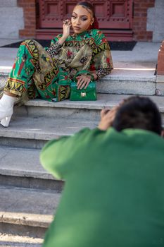 Fashion model poses in vibrant outfit on stone steps during urban photoshoot.