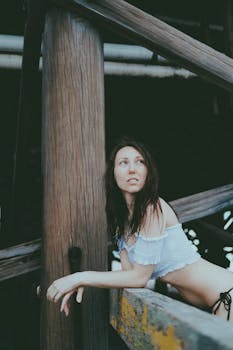 A fashionable woman poses under a pier at Daytona Beach in summer light.