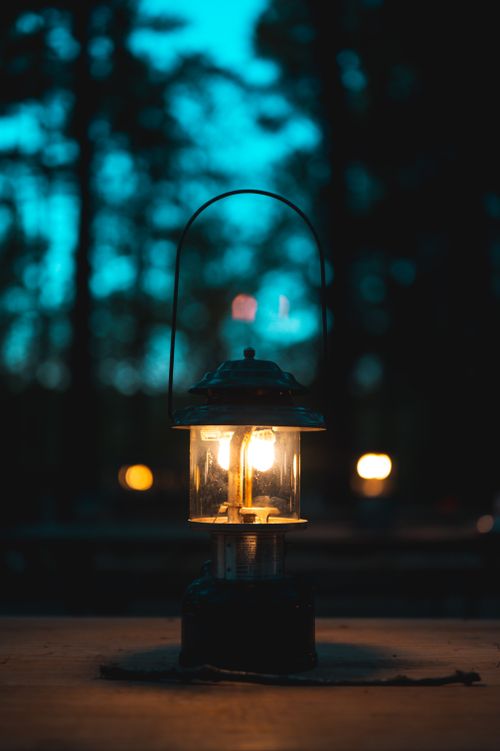 Free A classic lantern glowing in a tranquil forest setting during twilight, creating a serene ambiance. Stock Photo