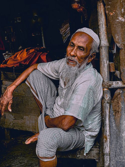Free An elderly South Asian man sitting thoughtfully in an outdoor setting in Bangladesh. Stock Photo