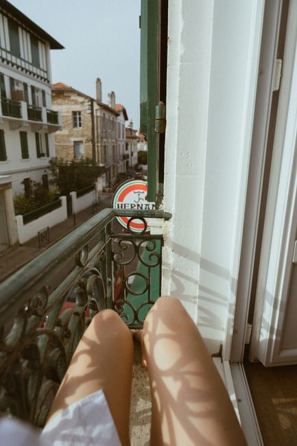 Enjoy a peaceful moment on a sunny balcony in Biarritz, overlooking charming French architecture.