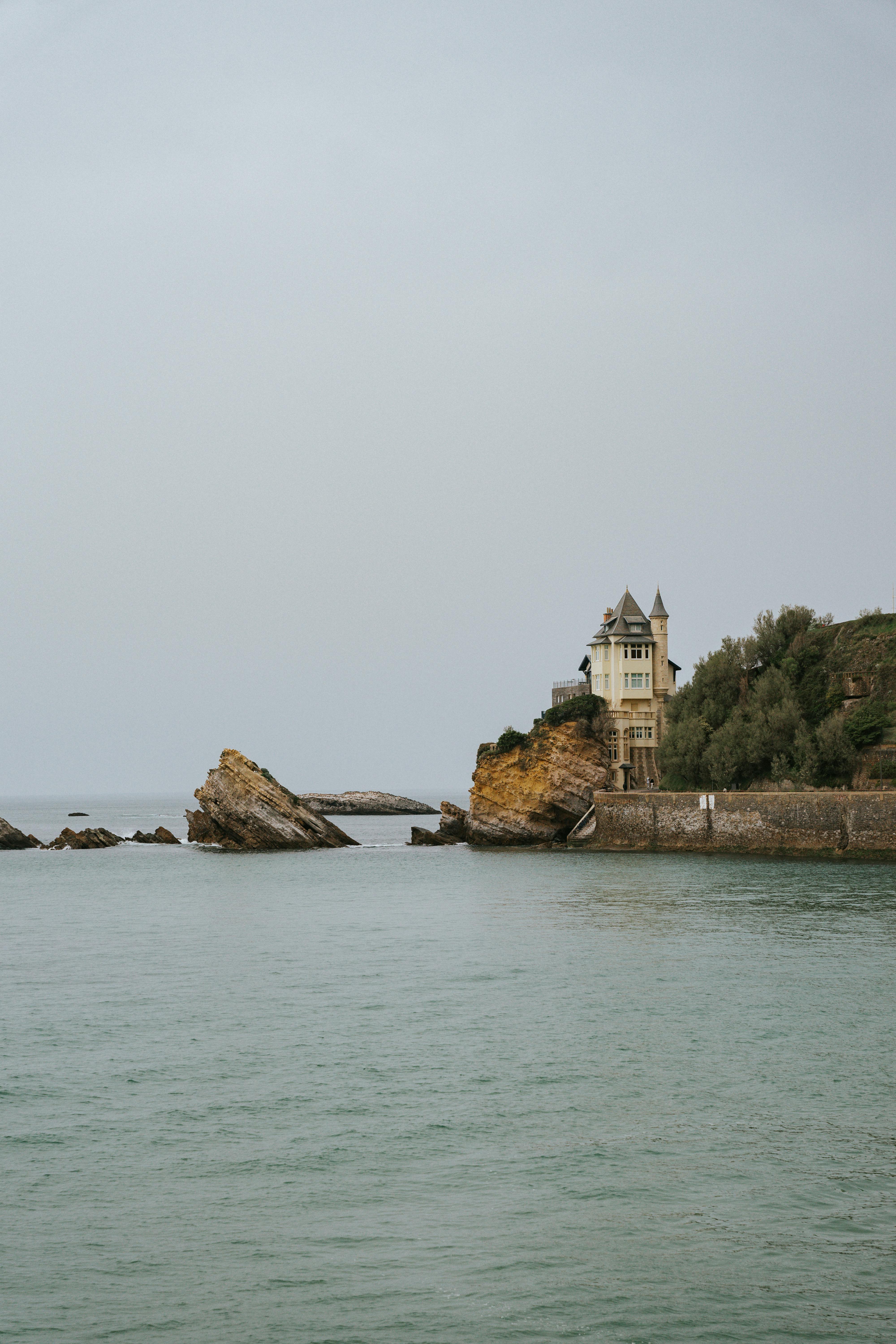 A scenic view of a historic villa located on the rocky coastline of Biarritz, France.
