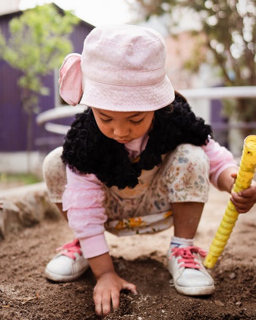 A Young Girl Wearing a Bucket Hat while Playing Sand