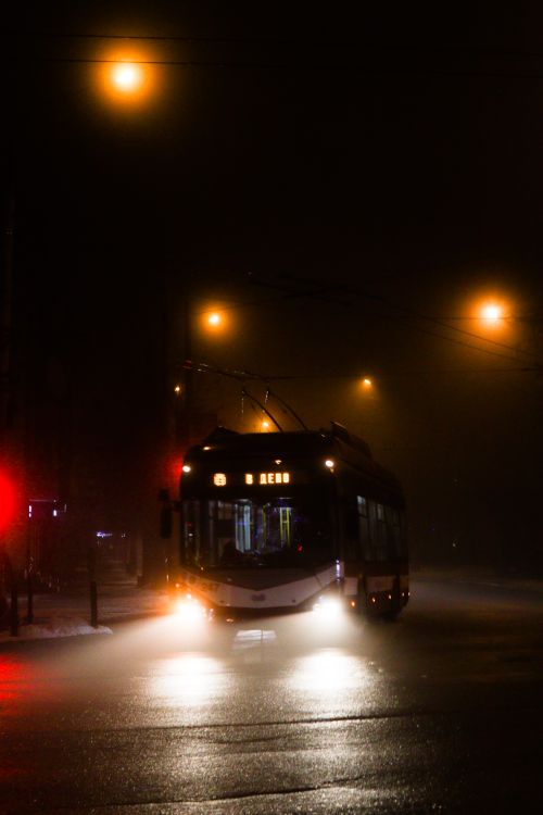 Free Moody urban scene of a bus with headlights on foggy night street. Stock Photo