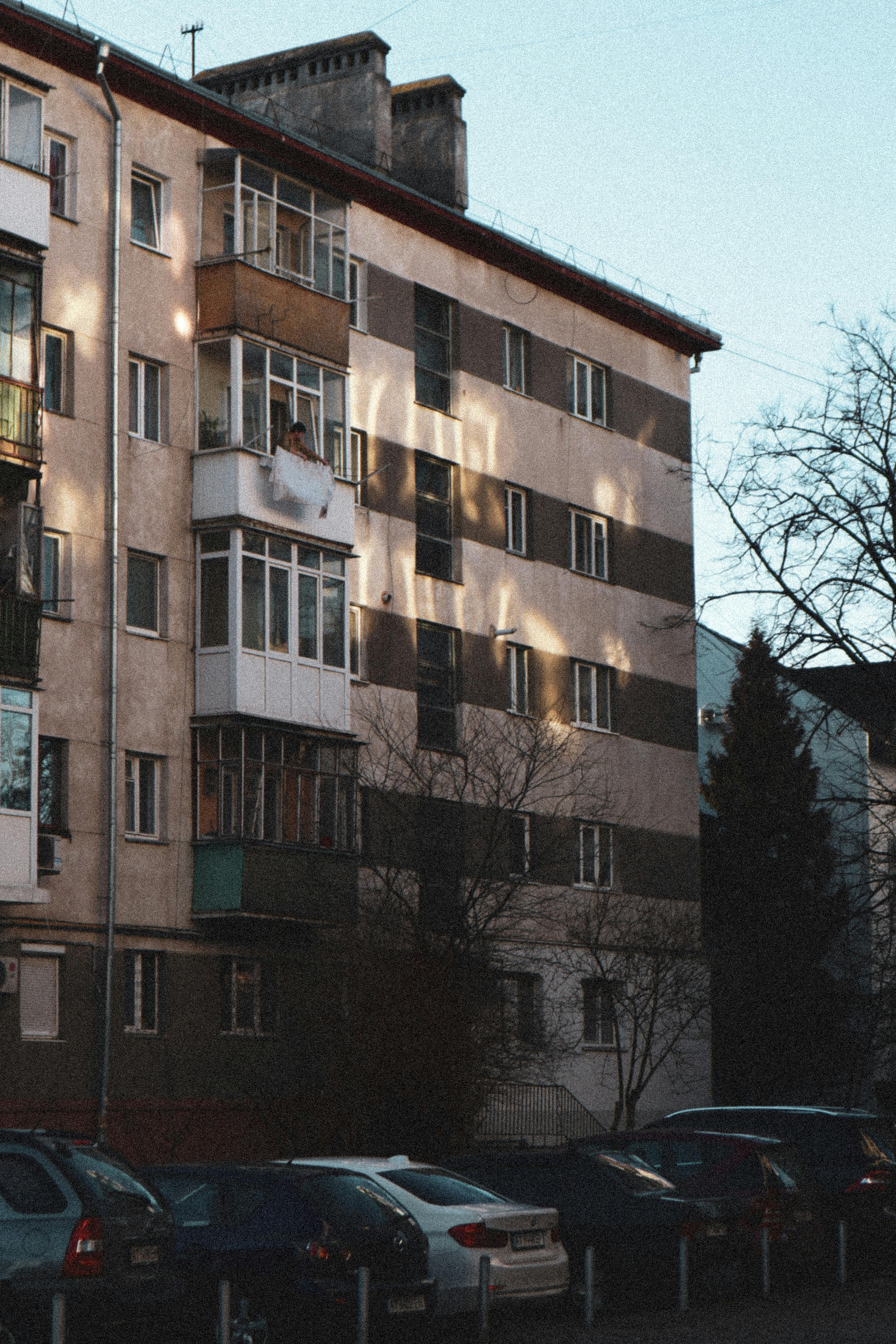View of a multi-story residential building with parked cars and natural lighting accents.