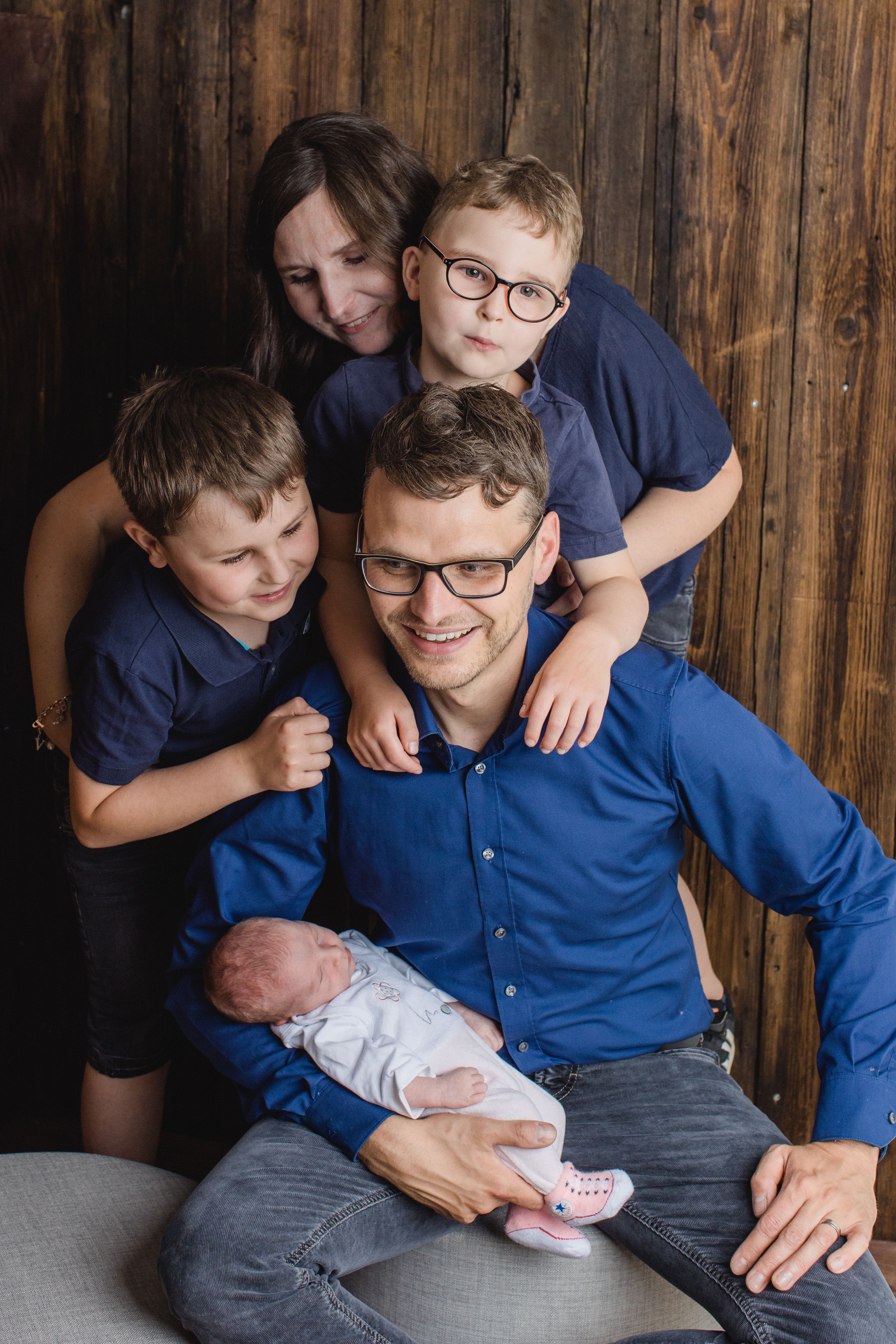 Smiling family of five posing together with newborn baby, capturing precious moments.