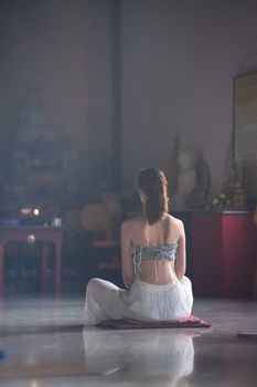 Young woman meditating alone indoors, cultivating mindfulness and tranquility.