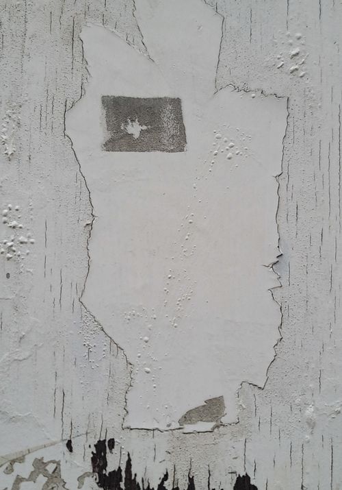 Free Close-up of a weathered wall with peeling white paint revealing underlying layers. Stock Photo