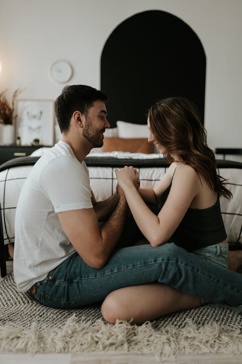 Free A Couple Sitting on the Floor and Holding Hands  Stock Photo