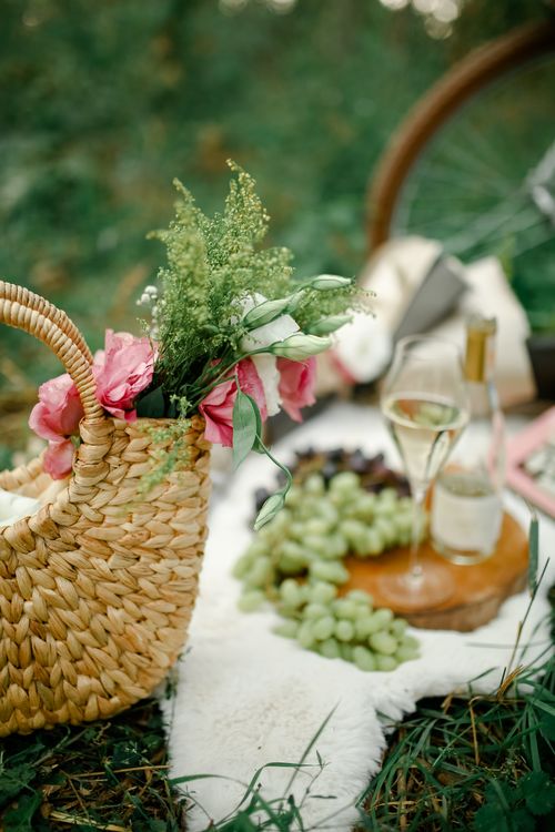 Free Woven basket with flowers and picnic setup on grassy field. Stock Photo