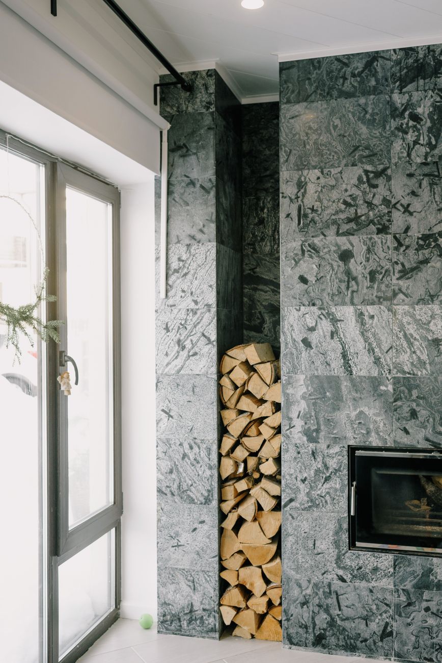 Cozy modern living room featuring a sleek fireplace and a neatly stacked woodpile.