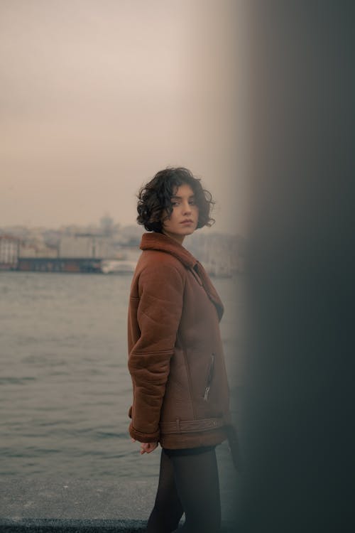 Woman in Brown Jacket Standing on Seaside