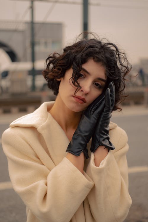 A Woman in Beige Coat With Black Gloves with Her Hands on Her Face