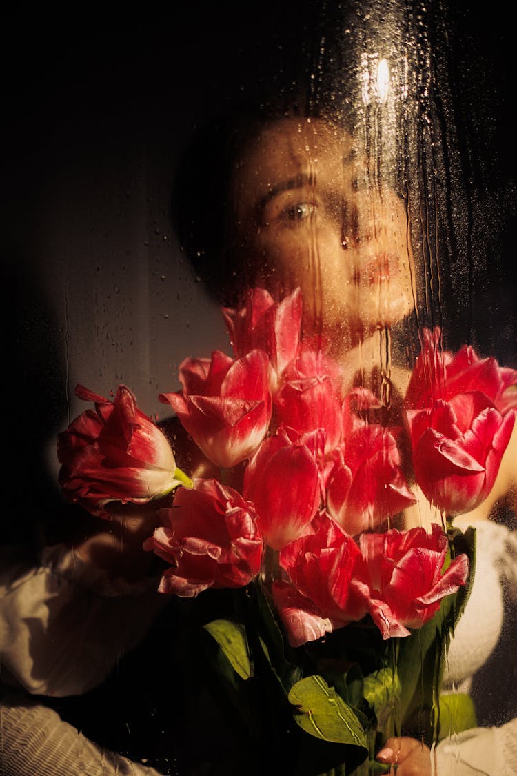 Woman Holding Flowers Behind Glass