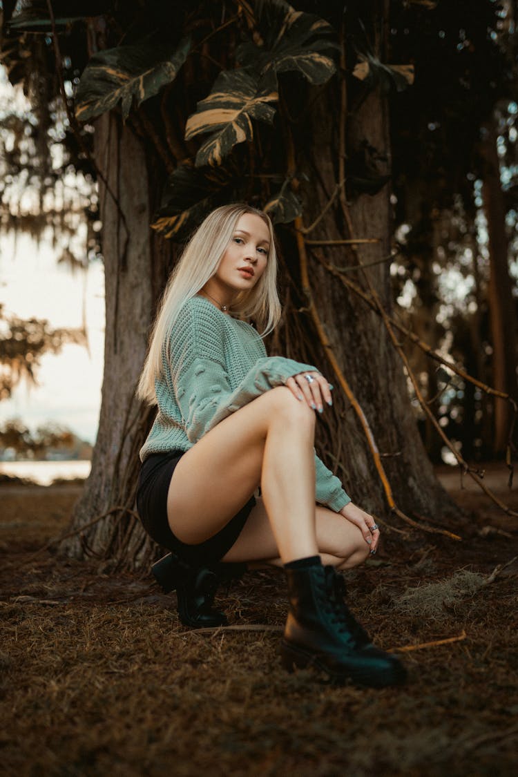 Woman Crouching On Ground Under Tree 