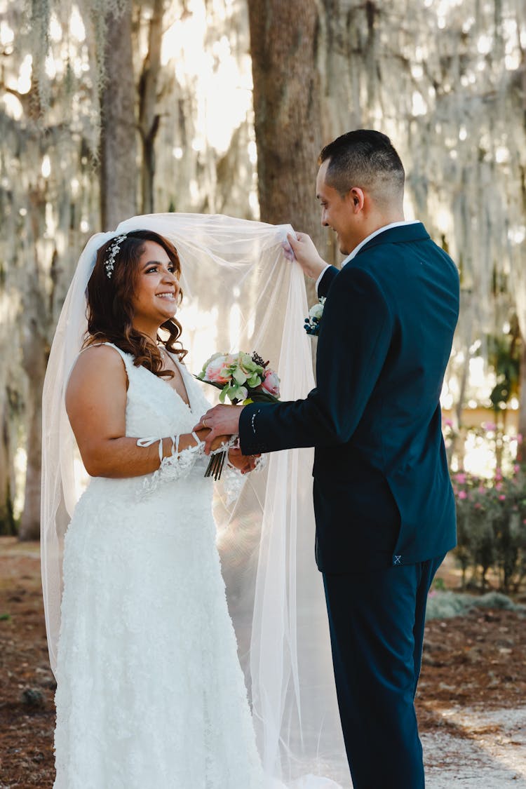 Groom Lifting Up Brides Veil