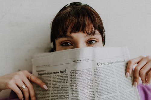 Young Woman Covering Half of Face with Newspaper