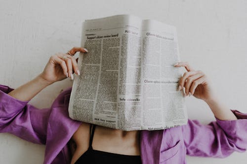 Unrecognizable Woman Covering Face with Newspaper