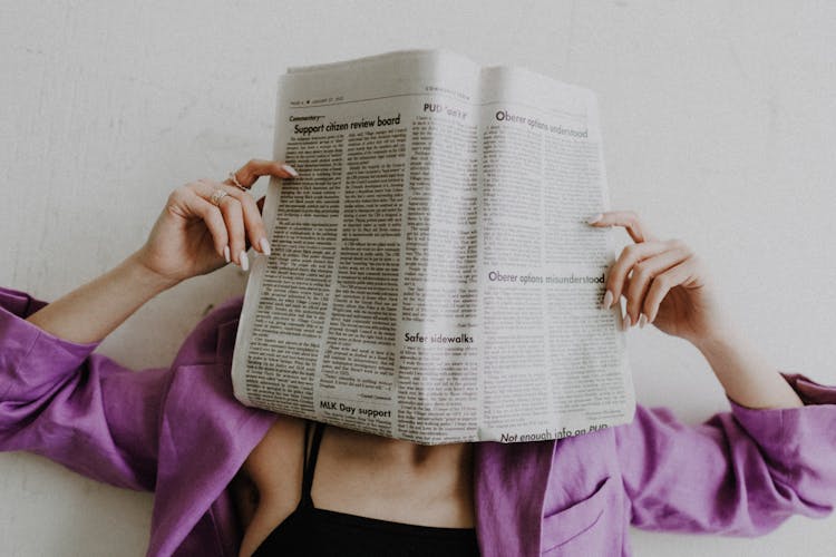 Unrecognizable Woman Covering Face With Newspaper