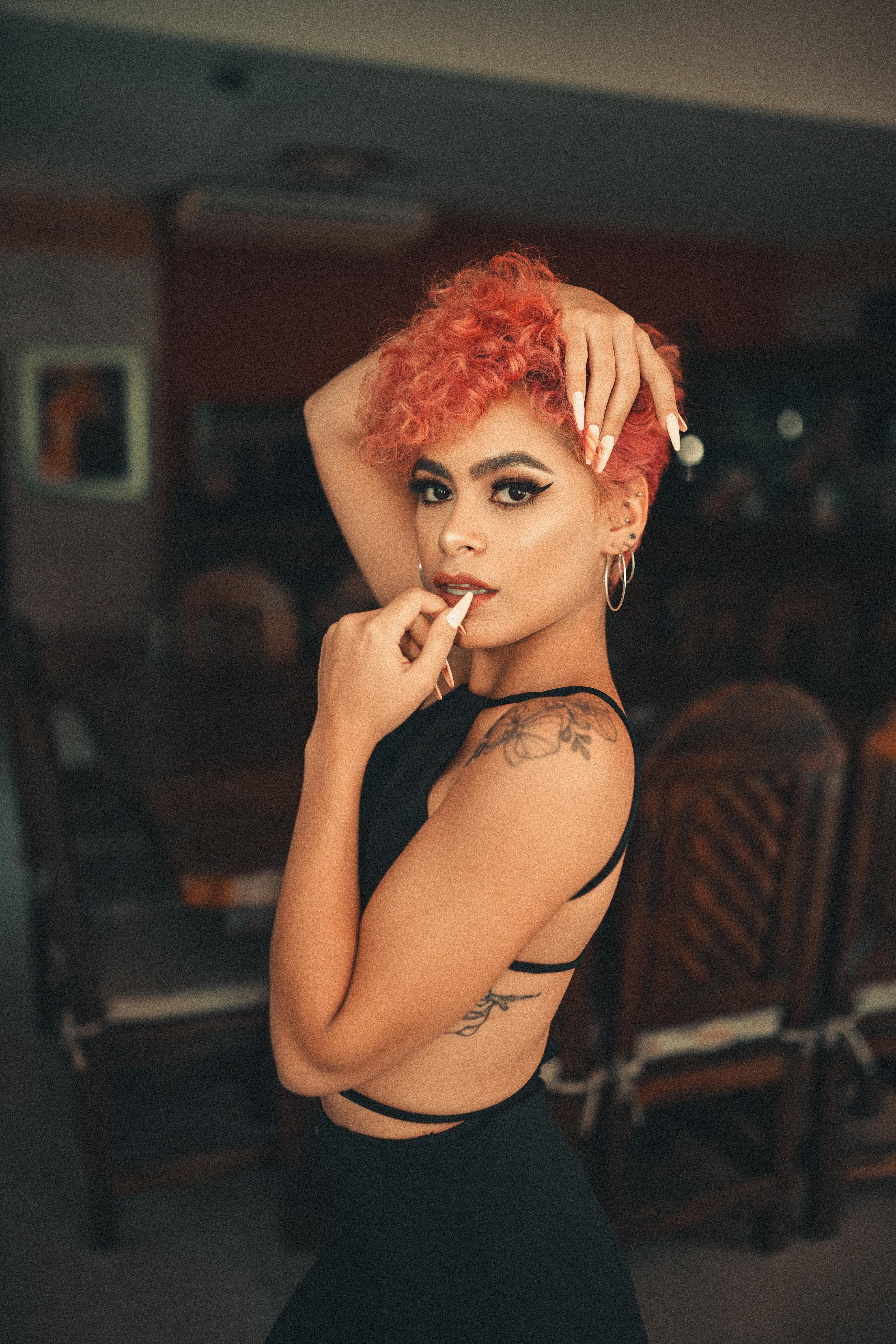 Portrait of a stylish woman with red hair posing confidently indoors. Perfect for lifestyle or fashion themes.